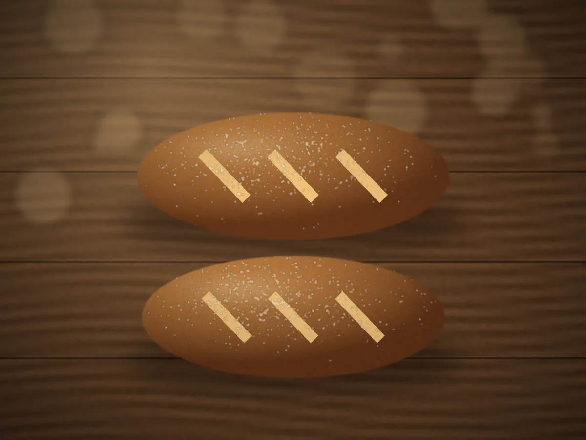 Two scored bâtard loaves with deep golden crusts cooling side by side